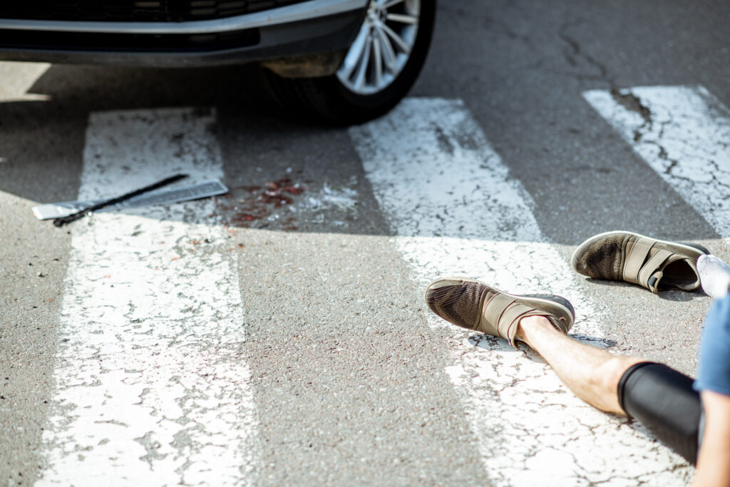 Injured pedestrian, night accident in Florida, lying on crosswalk near vehicle after collision