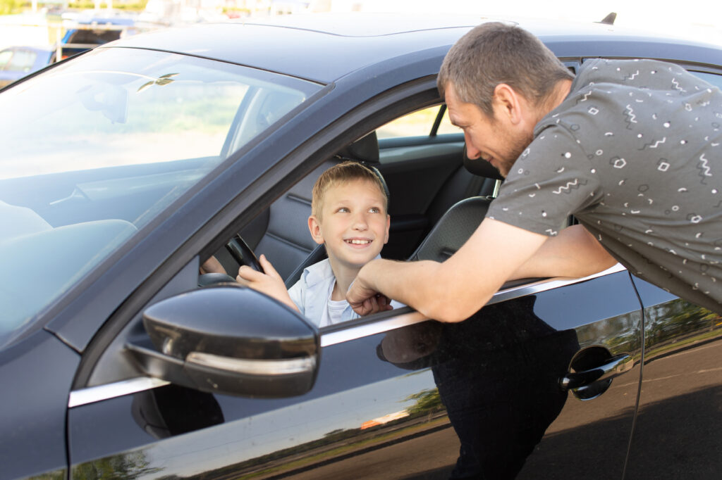 A father supervises his young son behind the wheel, illustrating Florida’s laws designed to help teens build skills safely.